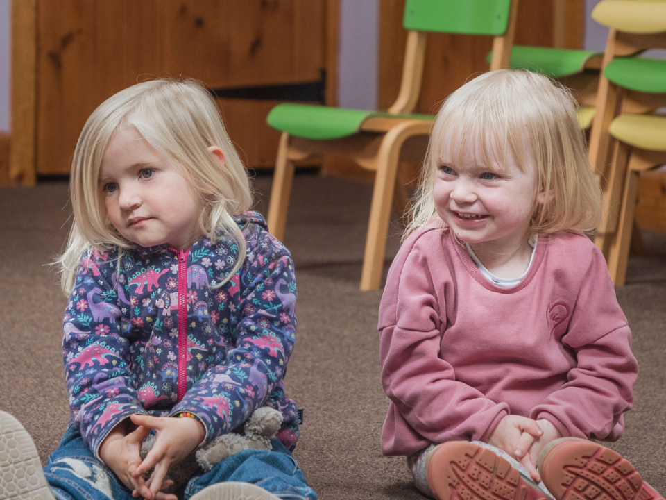 Two little girls sitting and smiling in a session