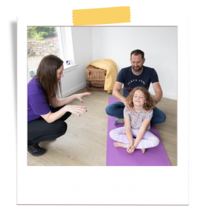 Girl with man and woman sitting on the ground inside