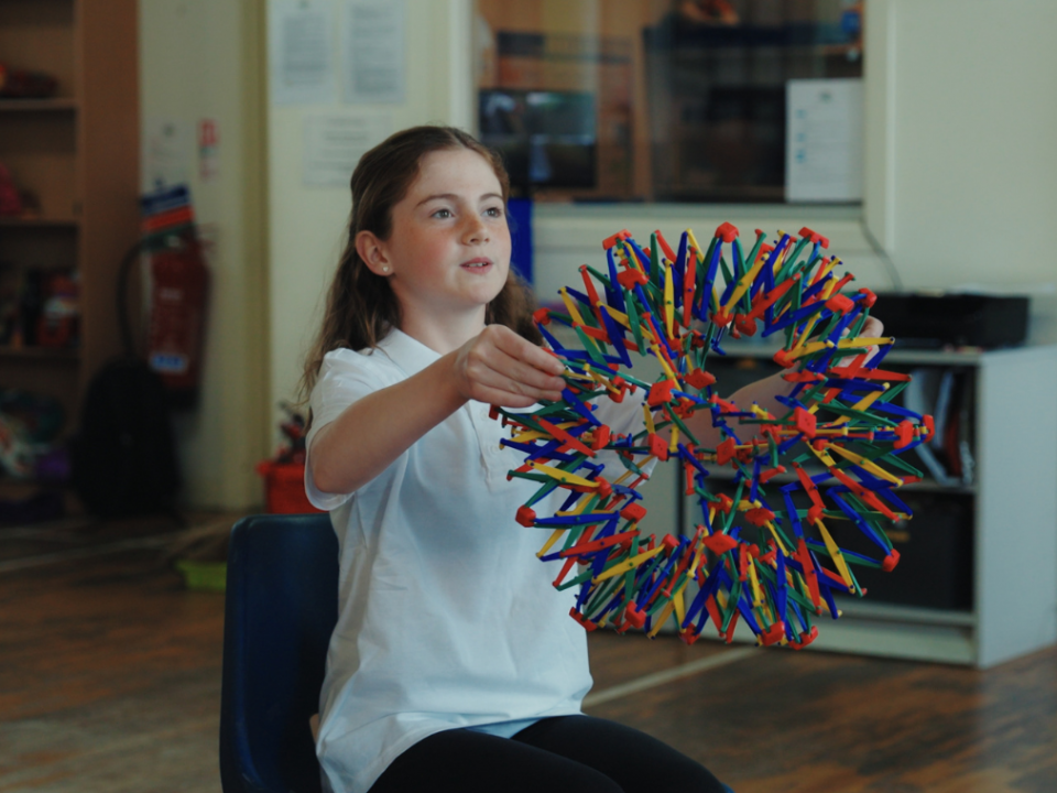 A child with the breathing sphere in Mind Marvels session, sat on a chair.