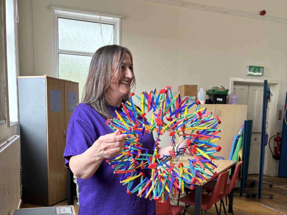 A session leader with breathing sphere at Mind Marvels session smiling as she opens it up.